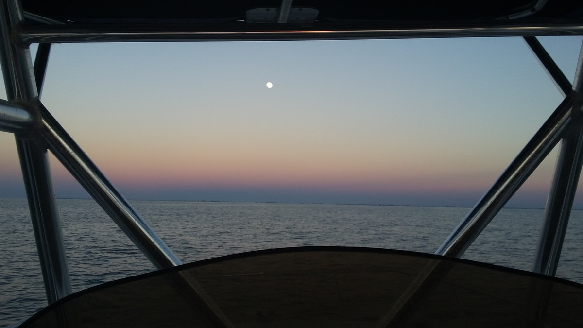 View forward from under the hardtop offshore at dusk with the moon rising
