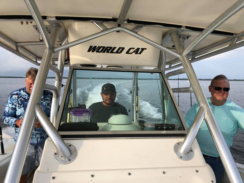Captain at the helm of a World Cat underway with two boat owners aboard